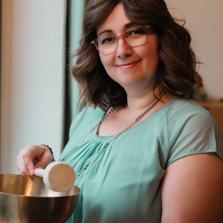 Frau in grünem Shirt hält eine Klangschale.